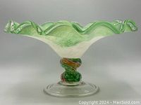 Side angle photo showing full ruffled green and white glass bowl with colorful twisted pedestal and clear base.