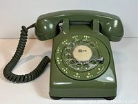 Front view of vintage green rotary dial telephone with coiled handset cord and rotary dial showing Area Code 416.