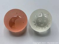 Pair of vintage glass paperweights, showing sun and moon designs, front view