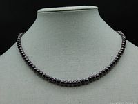 Front view of the dark gray pearl necklace displayed on a bust showing the size and arrangement of the pearls.