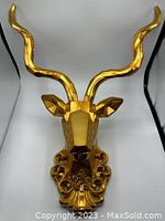 Front view of the assembled gold geometric deer head wall decor, showing detailed faceted design and decorative base.