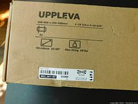 Photo of the cardboard box side showing product name Uppleva, mounting measurements 100-500 x 100-400 mm, TV size compatibility 37-55 inches, max weight 45 kg/99 lbs, IKEA SKU 902.267.97.