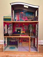 Front view of the large colorful three-storey KidKraft dollhouse showing interior rooms and features like spiral staircase and elevator