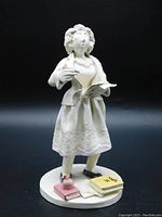 Full view of ceramic female scholar sculpture with papers, pen, and books on base