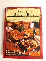 Front cover of the hardcover cookbook with dust jacket showing Italian food and title 'Italy in Small Bites' by Carol Field.