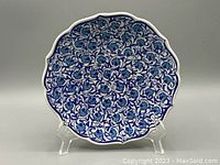 Front view of the ceramic wall plate showing intricate blue floral design on white background with scalloped edges.