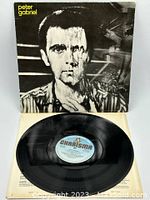 Vinyl record laid flat on top of the opened album cover, showing Charisma label on record and internal foldout with album credits.