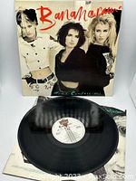 Vinyl record partially pulled out from the album cover showing the black disc and white label with text.