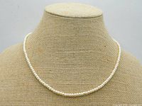 Front view of the 20 inch single strand blush cream pearl necklace displayed on beige fabric bust stand.