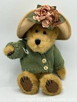Front view of Boyds Collection teddy bear wearing green sweater and beige hat with pink fabric flowers