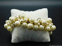 Close-up front view of the ivory pearl cluster bracelet showing the multiple sizes of faux pearls and gold chain.