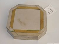 Closed view of the octagonal box showing metal exterior with gold and silver inlay and some surface tarnish.