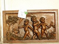 Front view of walnut relief panel showing three putti in high relief within molded frame