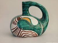 Front angled view of oval shaped Italian pottery vase with large curved handle and narrow neck, showing green, brown, white, and yellow abstract painted patterns.