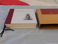 Front and spine view of thick Ethnographical Album book with original cardboard slipcover on a table.