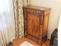 Front view showing cabinet door, ormolu mounts at corners, inlaid panels and lock escutcheon