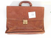 Front view of brown leather laptop case with handle and lock clasp, some wear visible.