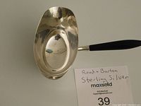 Angled top view showing the inner bowl of the sauce boat and wood handle with handwritten note about brand and material.