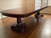 Angled view showing full table top, border carving, pedestals and feet