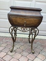 Full view of the decorative storage chest on metal base, showing front, legs, and top lid.