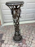 Full view of metal pedestal stand showing overall structure, decorative scrolled accents, round faux alligator skin top.