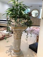 Full view of faux potted plant sitting atop colonial-style pedestal in room setting