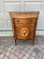 Front view of end table showing veneer pattern, drawer, door with floral medallion