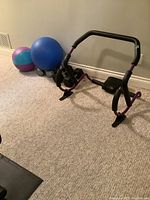 Wide view showing ab roller, yoga ball, beach ball, metal and rubber-coated dumbbells arranged on carpet