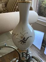 Side angle of the white porcelain vase showing floral and gold detail