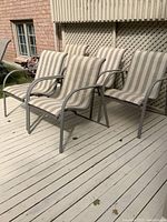 Set of five patio chairs arranged on a wooden deck, showing the full view of their structure and fabric.