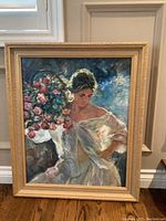 Full view of signed framed oil painting leaning against wall