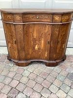 Frontal view of solid wood serpentine console cabinet with two doors and scalloped base