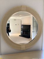 Front view of the circular mirror reflecting a living space with fireplace and doors.