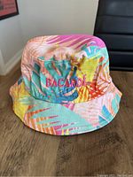 Front and side view of colorful Bacardi bucket hat with tropical leaf design on denim.