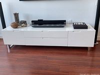 Front view of console table placed against wall with decorative vases and electronic device on top