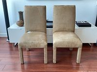 Front view of two beige suede parsons chairs, showing upholstery condition and style.