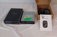 Photo shows two internal optical drives side by side and a small cardboard box containing a Nortel Networks USB Phone Adaptor, remote control, and instruction manual.