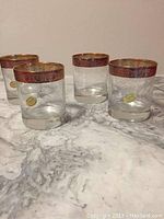 Set of four crystal glasses with wide gold rims on a marble surface