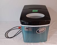 Front view of Igloo table top ice maker with silver stainless steel exterior, black lid with viewing window, and visible power cord.