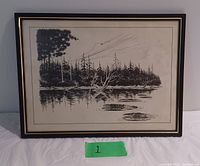 Photo of black and white lake print framed with glass and black and gold trim.