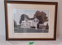 Framed limited edition print showing a white house with surrounding trees and a woman in period dress outdoors.
