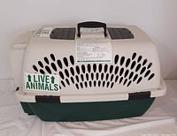 Side view showing the beige upper part with ventilation holes and the 'LIVE ANIMALS' sticker. Black handle on top for carrying.