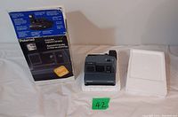 Polaroid Impulse instant camera with original box and styrofoam insert visible on a white cloth background with placeholder number 42.