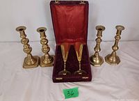 Four brass candlesticks and two tall brass wine cups in a lined box