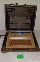 Front angle view of the typewriter with the case lid open, showing keyboard and platen roller.