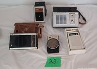 Front view of five vintage transistor radios arranged on white background showing brands Philips, Sony, Hitachi, Cosmosonic, and Riviera