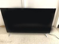 Front view of the Vizio 43 inch flat screen TV showing black screen and silver legs on a tiled floor.