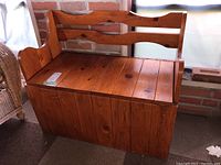 Front view of pine storage bench showing wood grain and hinged seat.