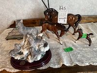 Full view of all porcelain and ceramic animal figurines including horses and wolves, and ceramic coaster on lace cloth