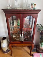 Full view of the wooden display cabinet with glass doors and shelves, showcasing its design and structure.